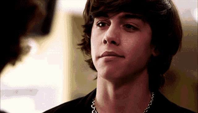 a young man wearing a black shirt and a chain around his neck