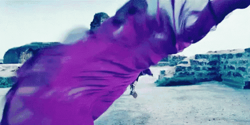 a woman in a purple dress is dancing in front of a brick wall .