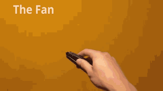a person is holding a pair of scissors in front of a yellow wall that says the fan on it