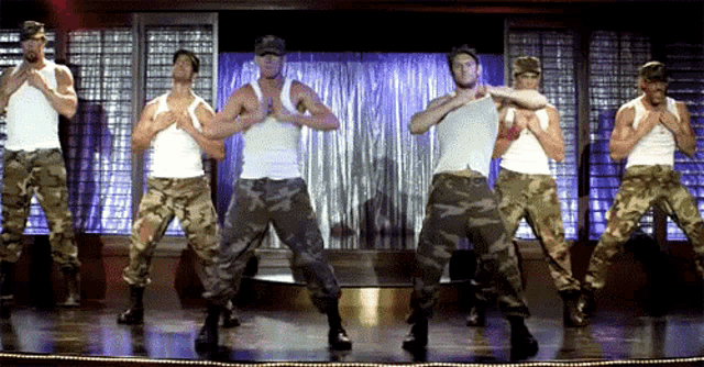 a group of men in camouflage pants and white tank tops are dancing on a stage