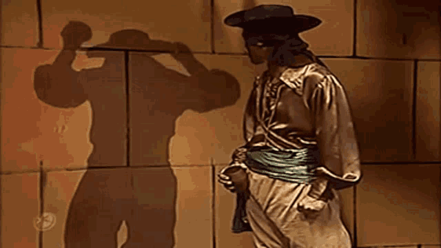 a man in a cowboy hat is standing in front of a brick wall