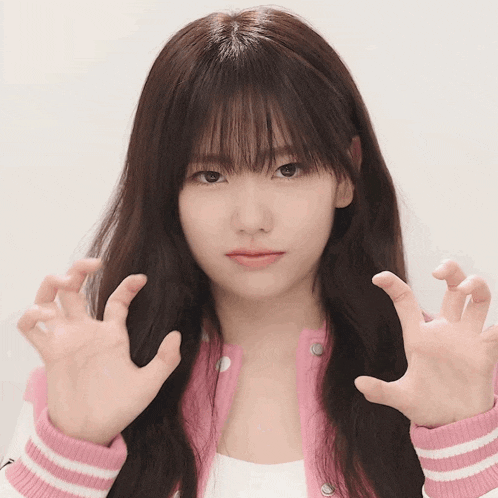 a girl with long hair and bangs is wearing a pink and white jacket