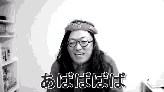 a black and white photo of a man with long hair and glasses wearing a bandana .
