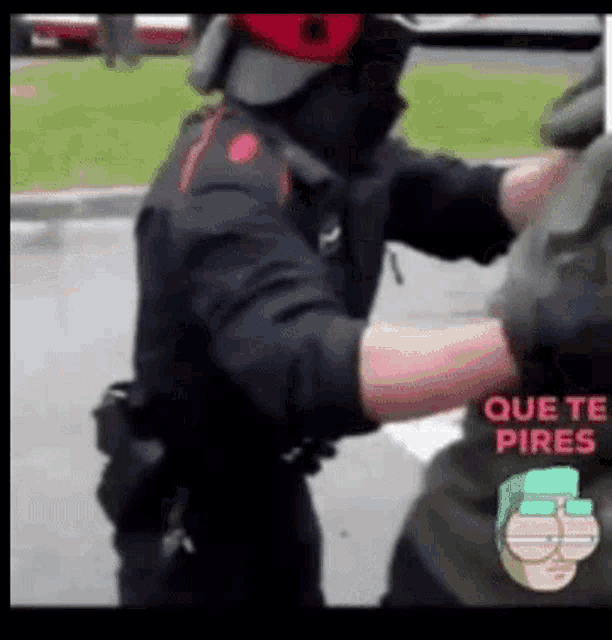 a police officer is holding a man in a black shirt that says que te pires on it .