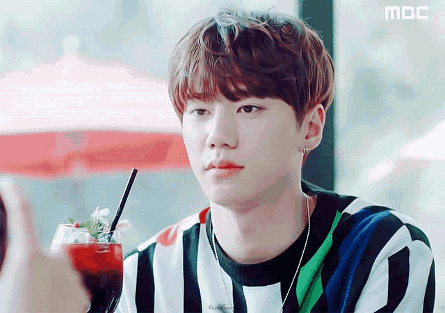 a young man is sitting at a table with a drink in front of him and the word mbc is on the bottom right