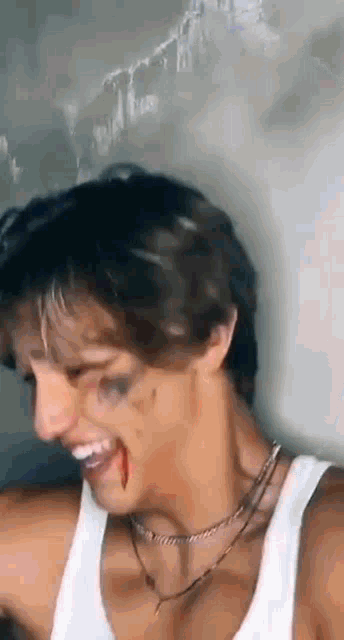 a man with blood on his face is wearing a white tank top .