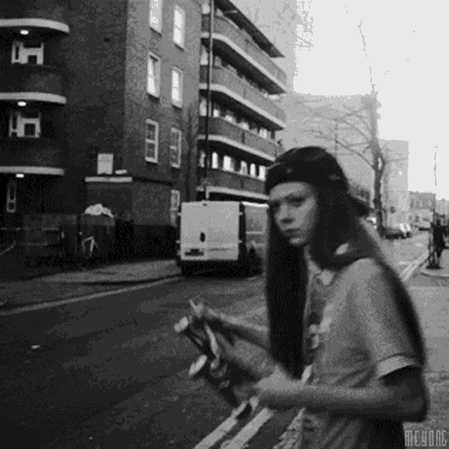 a black and white photo of a person holding a skateboard with the letters mcvdrc on the bottom