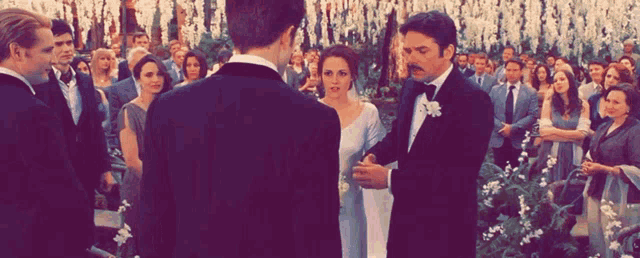 a man in a tuxedo stands next to a bride and groom