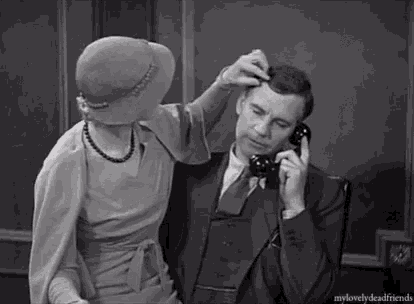 a black and white photo of a woman touching a man 's head