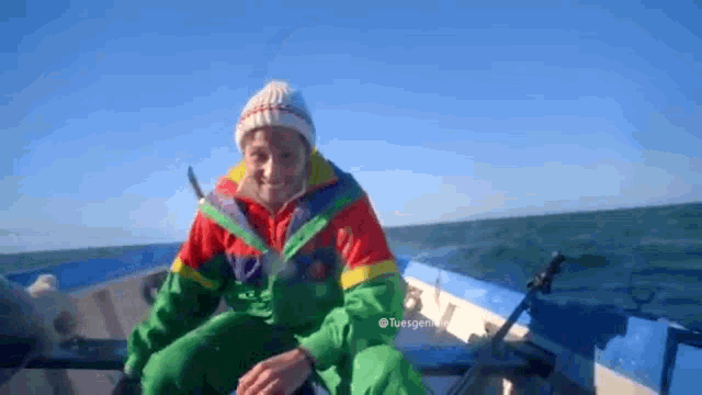 a man in a colorful jacket sits on a boat in the ocean