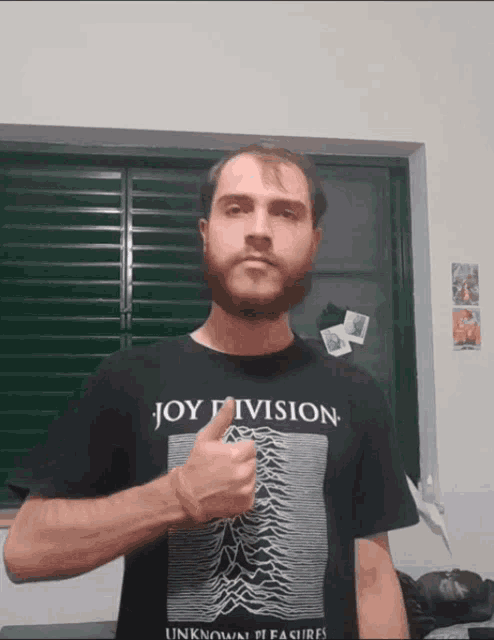 a man wearing a joy division t-shirt giving a thumbs up