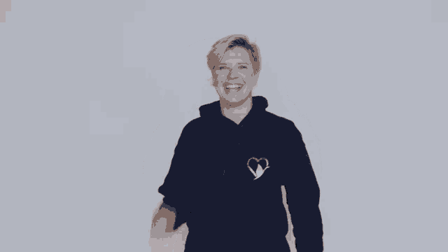a woman wearing a blue sweatshirt with a heart on the front