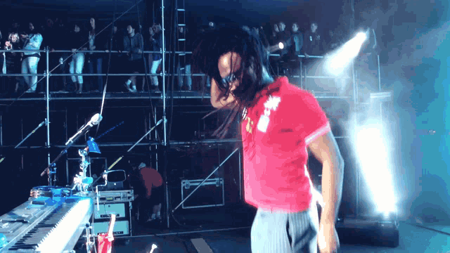 a man in a red shirt is dancing on a stage in front of a crowd