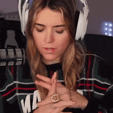 a woman wearing headphones and a ring on her finger is sitting in front of a microphone .