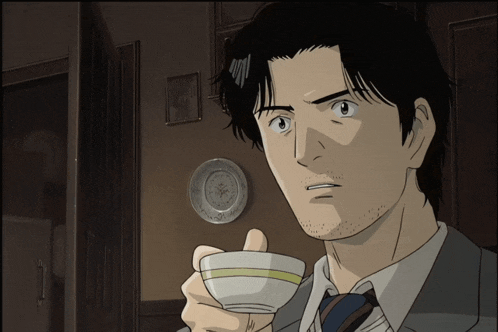 a man in a suit and tie is holding a small cup