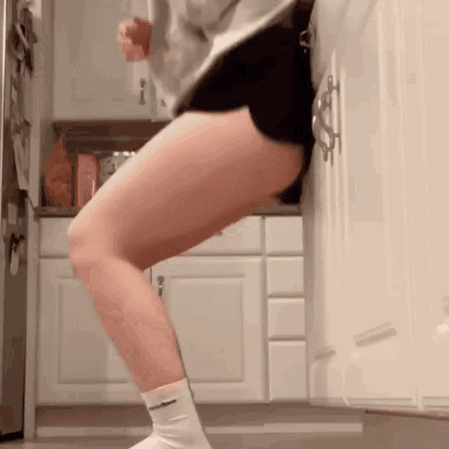 a woman is standing in a kitchen wearing shorts and socks that say nike