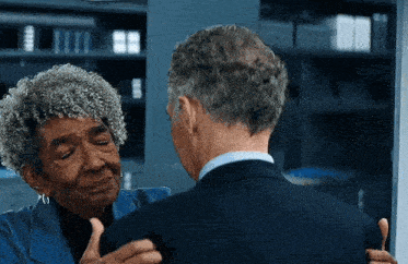 an older woman is hugging a man in a suit