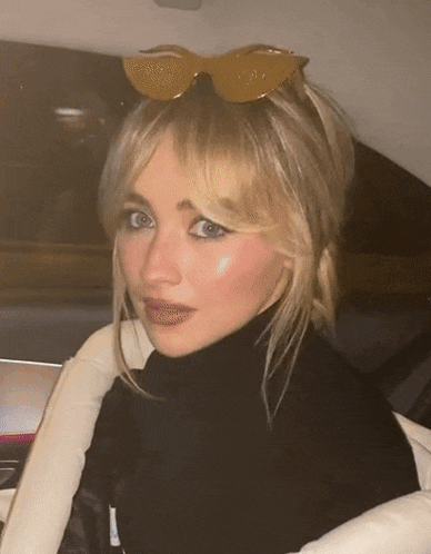 a blonde woman wearing sunglasses and a black turtleneck