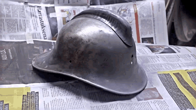 a helmet sits on top of a pile of newspapers including one that says harrastollena