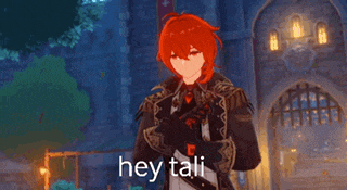 a man with red hair is standing in front of a building with his hands folded and the words hey tali above him .