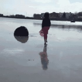 a woman in a red skirt walks on a beach