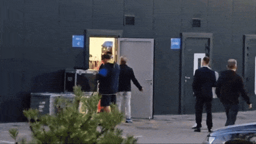 a group of people are standing outside of a building with a sign on the door that says ' exit 4 '