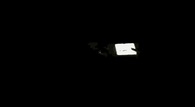 a shirtless man laying on a bed holding a cell phone with the letter s on the screen