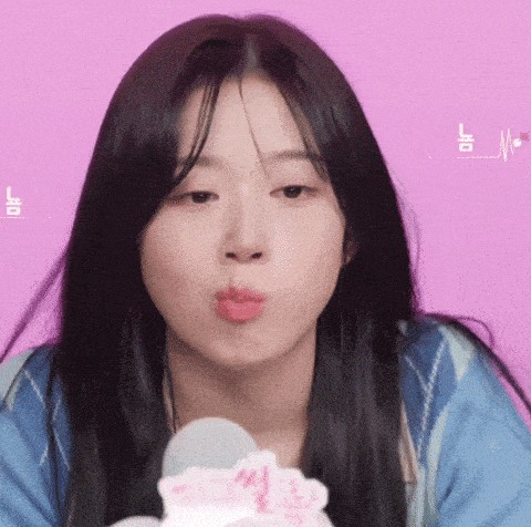 a close up of a woman blowing a kiss with a pink background