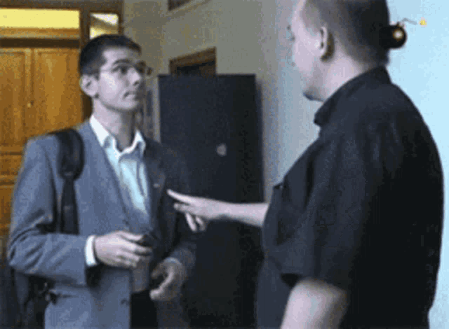 a man in a suit is talking to another man