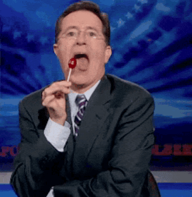 a man in a suit and tie eating a lollipop