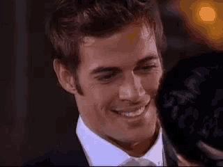 a man in a suit and tie is smiling while looking at another man .