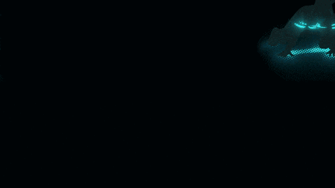 a man in a suit stands in a dark room with a light shining on him