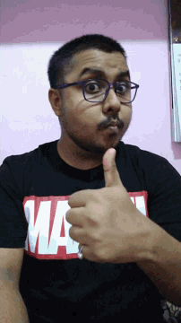 a man wearing glasses and a black shirt that says ' marvel ' on it