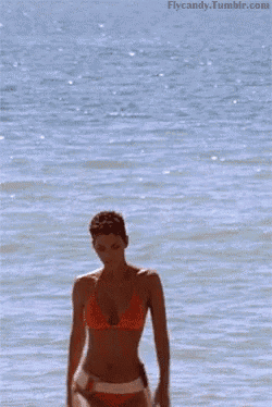 a woman in an orange bikini is standing in the water with the website flycandy.tumblr.com visible in the corner