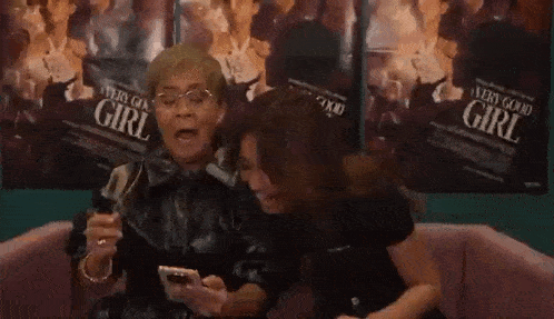 two women are sitting next to each other with their mouths open .