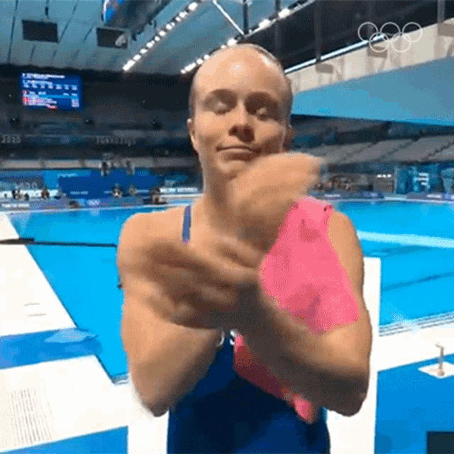 a woman in a blue bathing suit is clapping her hands in a swimming pool .