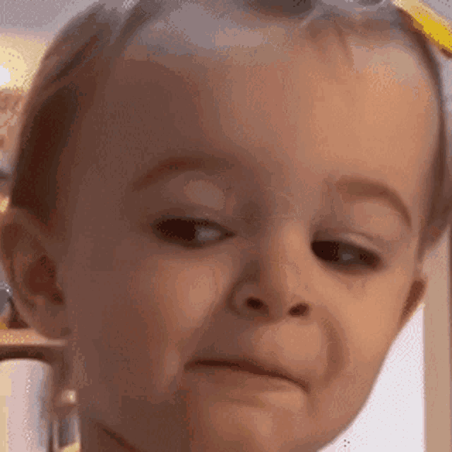 a close up of a baby making a funny face with a yellow bow in her hair .