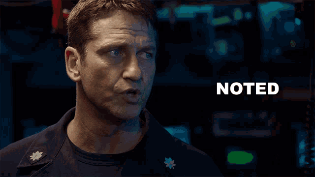 a man with a badge on his chest has the word noted above him
