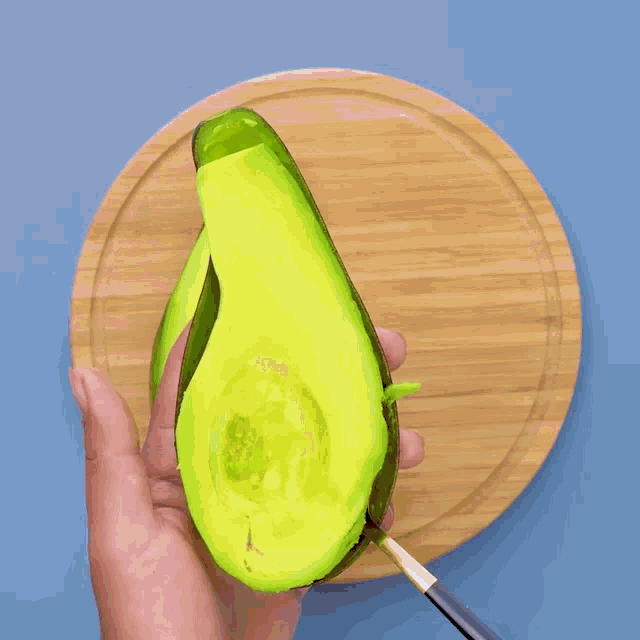 two avocados on a wooden plate with chocolate being poured on them