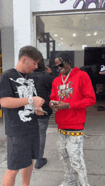 a man wearing a red hoodie that says sonic talks to another man