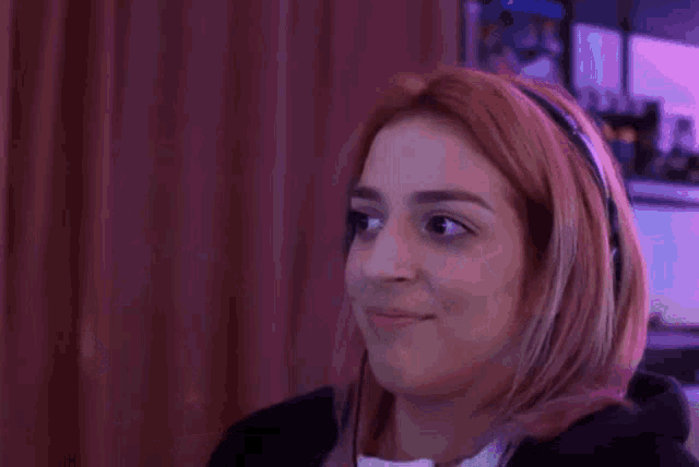 a woman wearing headphones is holding a white remote control .