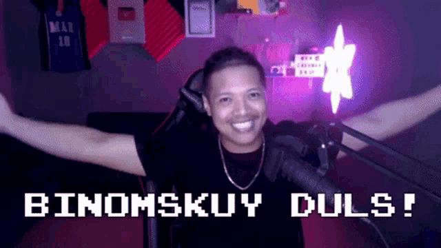 a man is sitting in front of a microphone with his arms outstretched and the words binomskuy duls on the bottom