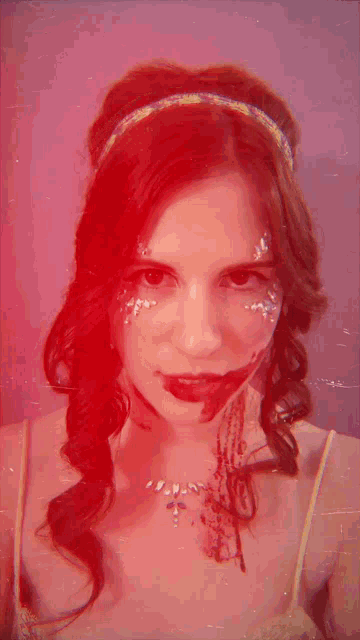 a woman with red hair and rhinestones on her face smiles