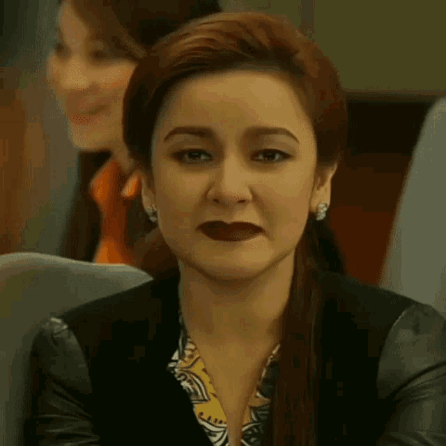 a woman with red hair is wearing a black leather jacket