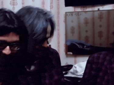 a man and a woman are sitting in front of a wall with a sign that says " lit " on it