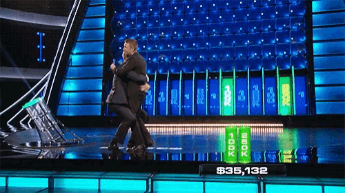 two men hugging on a stage with a sign that says $ 35,132 in front of them