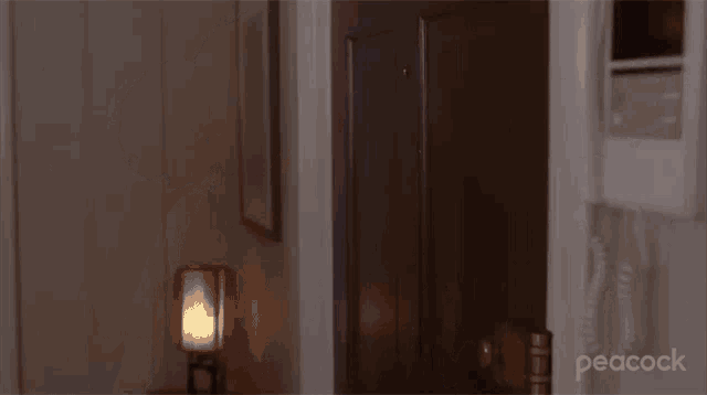 a woman in a blue sweatshirt is standing in front of a door and talking on a phone .