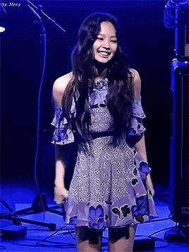 a woman in a purple dress is standing on a stage .