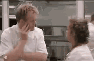 a man and a woman are sitting at a table in a kitchen .