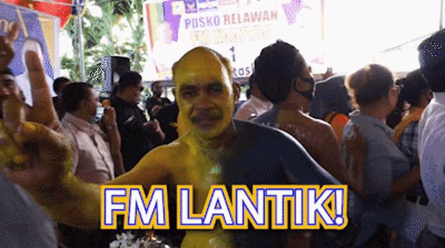 a man with yellow paint on his face is giving a peace sign in front of a sign that says posko relawan fm mantau